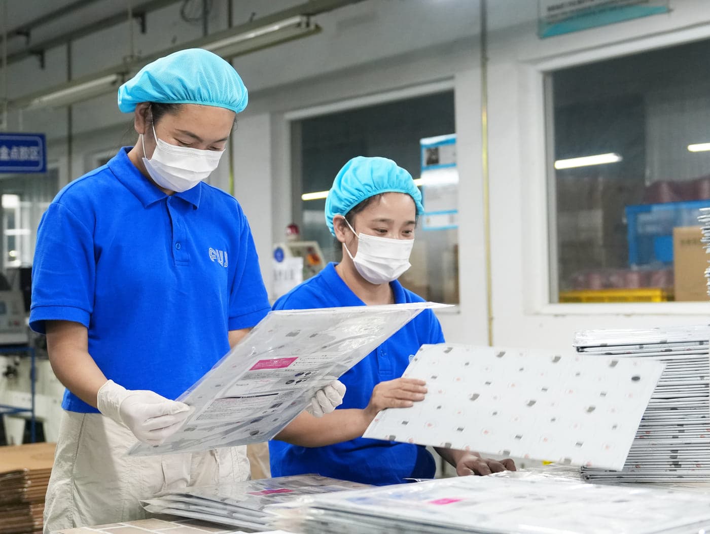 稼働中の製造設備のそばで製品を検査する担当者